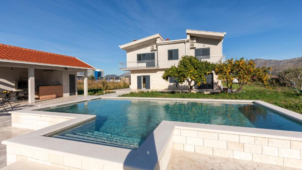 una piscina davanti a una casa di Villa Dolina Opuzen by Villas Guide a Podgradina