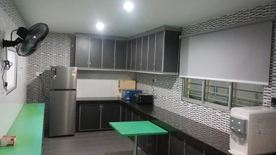 een keuken met zwarte kasten en een groene tafel bij mulia homestay in Teluk Intan