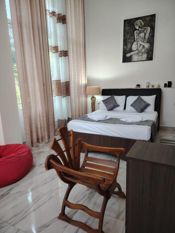 a bedroom with a bed and a wooden chair at Charlotte Inn in Kandy