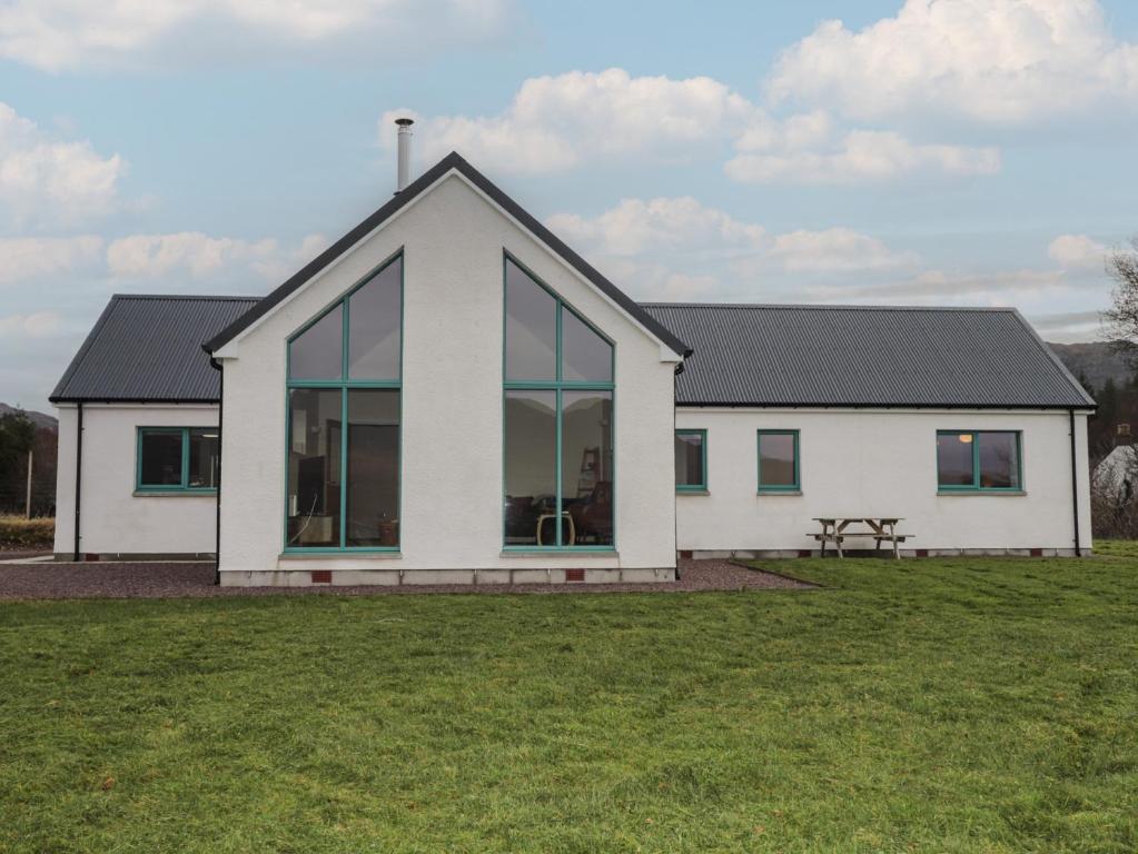 a white house with glass windows on a field at Sonas in Strathcarron