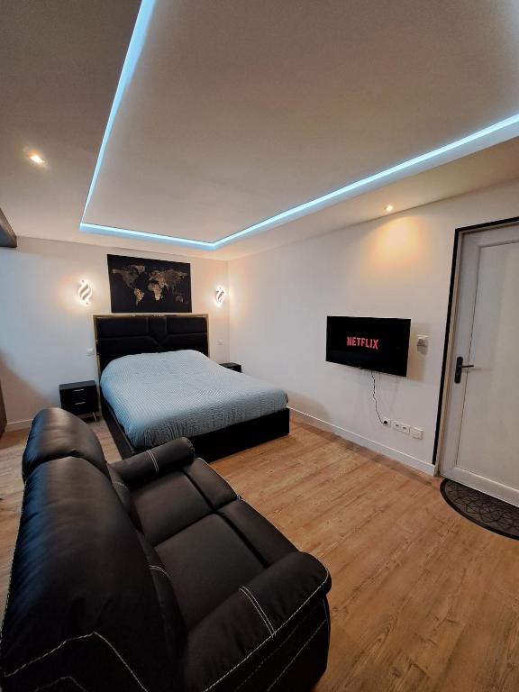 a bedroom with a bed and a couch and a tv at La suite d'Isa in Lens