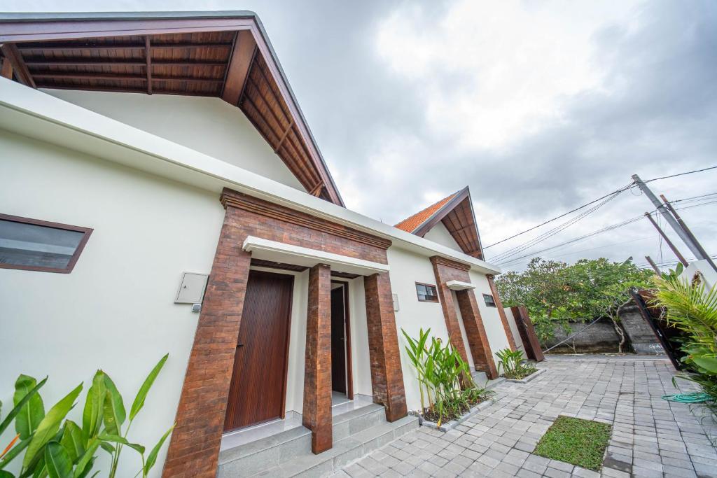 a white house with a brown door and a courtyard at Svadarma Bali Villa in Darmasaba