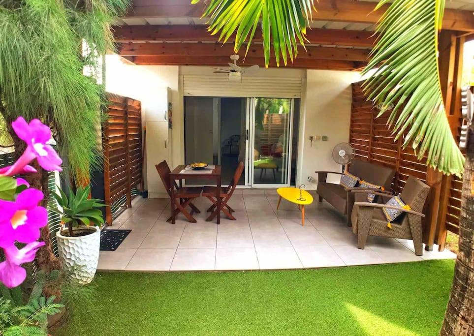 een patio met een tafel en stoelen en groen gras bij Ti Kaz Lol in Saint-Paul