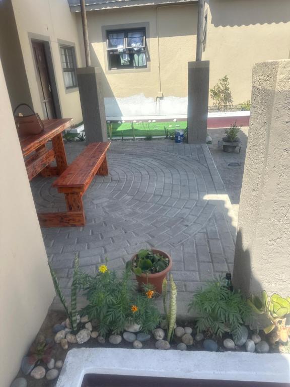eine Terrasse mit zwei Bänken, Pflanzen und Blumen in der Unterkunft Suuka Guest House in Walvis Bay