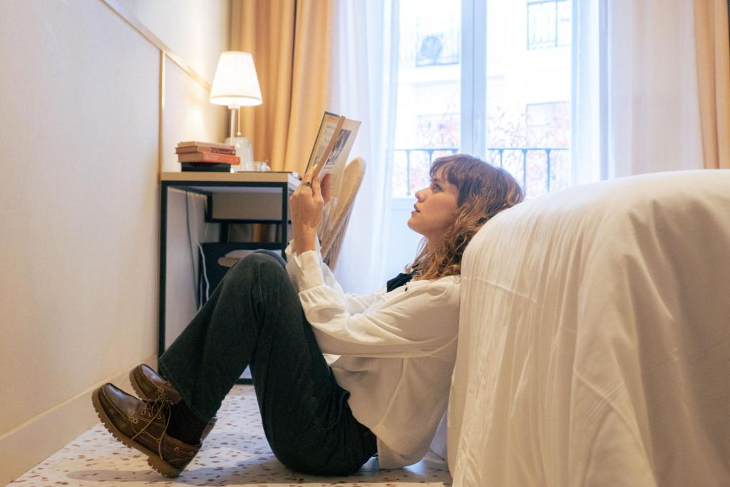 a woman sitting on the floor reading a book at BYPILLOW The Citadel in Madrid