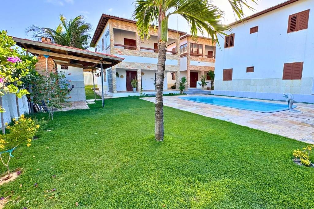 a backyard with a palm tree and a swimming pool at Maré · Casa Maré in Aracati
