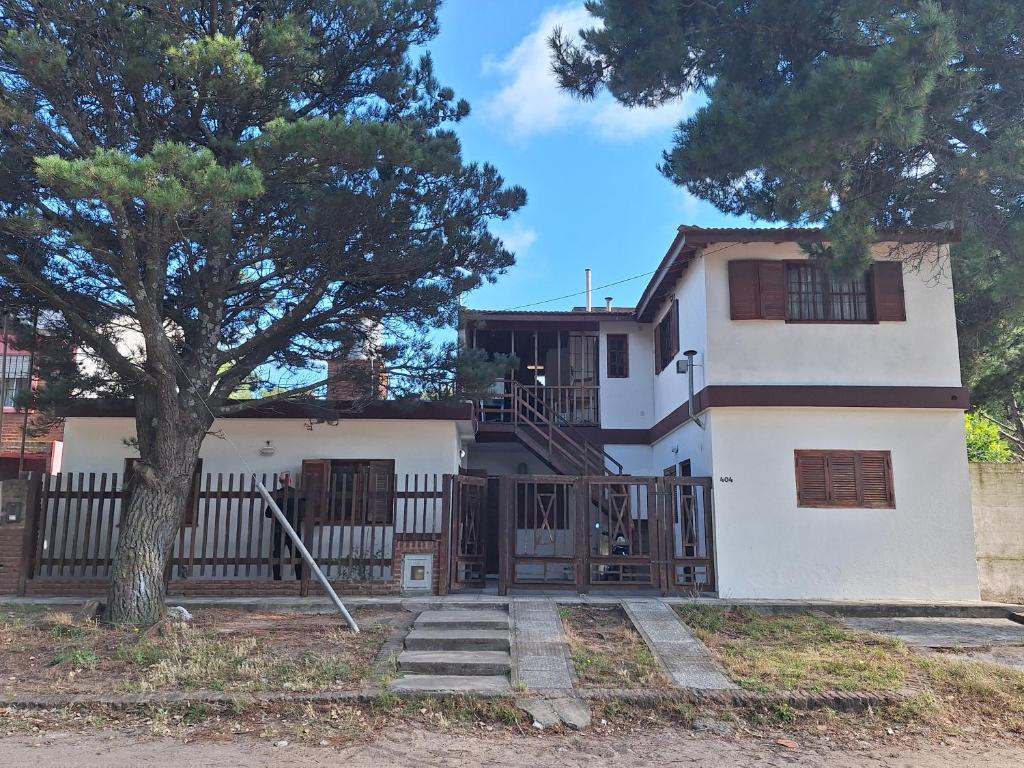 a white house with a gate and a tree at Departamentos MDA MIC in Mar de Ajó