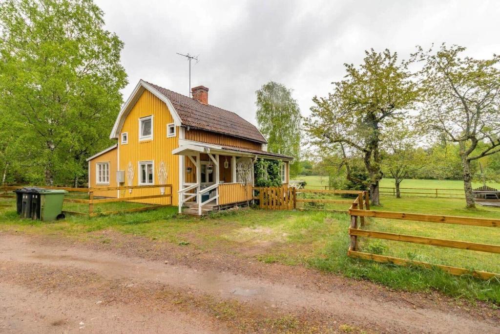a yellow house with a fence next to a field at KAL911-Hjorted-Sandekulla in Gissebo