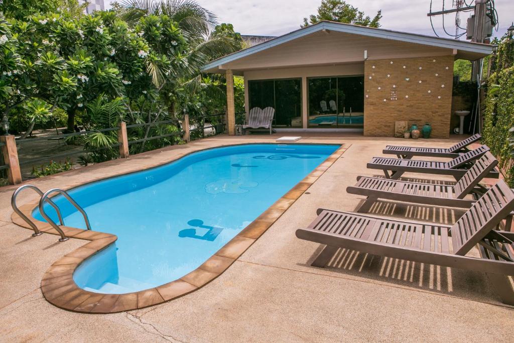 a swimming pool with lounge chairs next to a house at United Place in Bangsaen