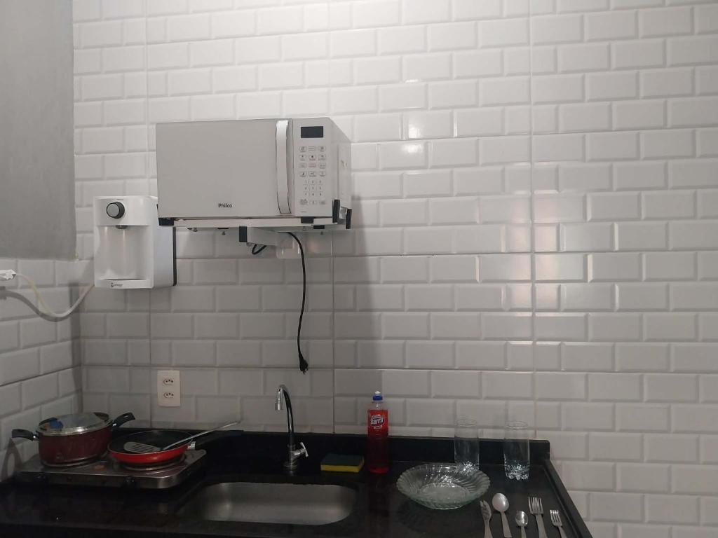 een aanrecht met een spoelbak en een magnetron bij KITNET ELVIS PRESLEY - Largo do Machado in Rio de Janeiro