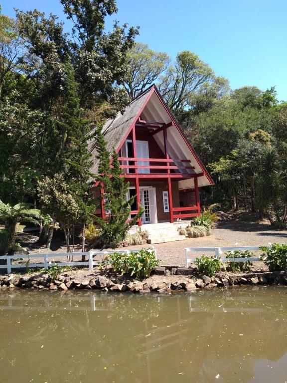 a red house next to a body of water at Cabana da Serra in Riozinho