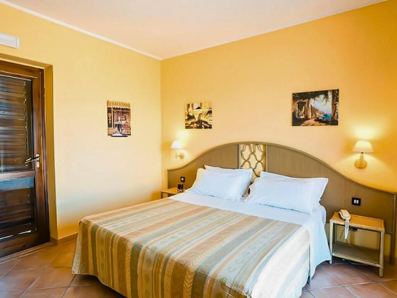 a hotel room with a large bed with white pillows at Aura Club Porto Rhoca in Squillace