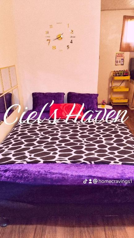 een slaapkamer met een paars bed met een klok aan de muur bij Ciel's Haven Free Breakfast in Binangonan