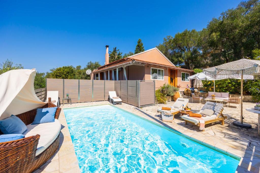 a swimming pool with chairs and a house at Dimitris Cottage in Apergátika