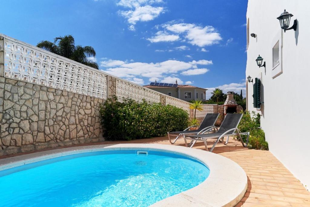 a swimming pool with two chairs and a wall at Sunset Villa in Ferragudo