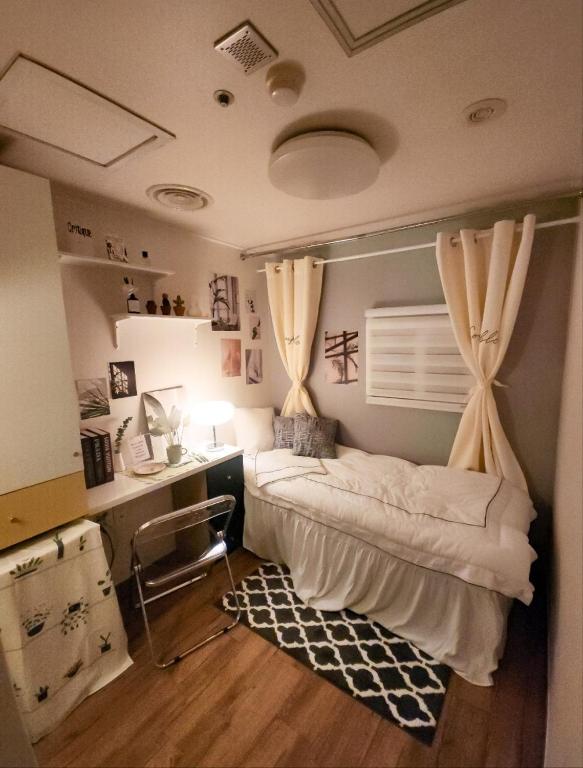 a bedroom with a bed and a desk and curtains at Bomnal Stay 봄날스테이 in Samgong