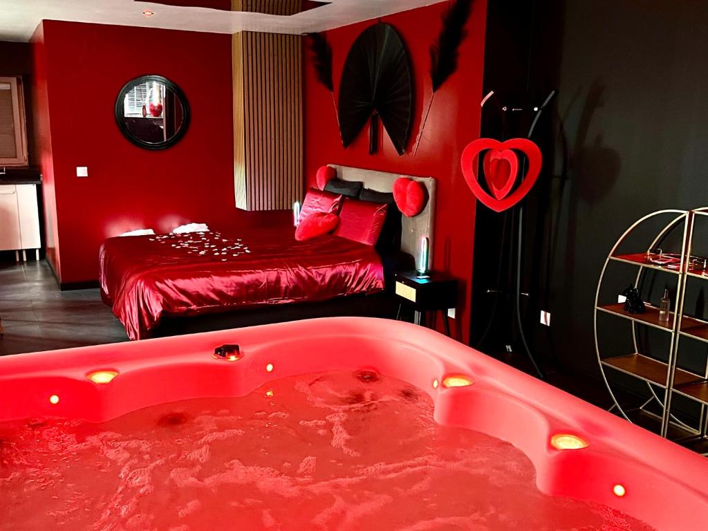 een rode kamer met een bad en een bed bij Redroom, Spa, Sauna, cheminée, romantique pour 2 in Quimperlé