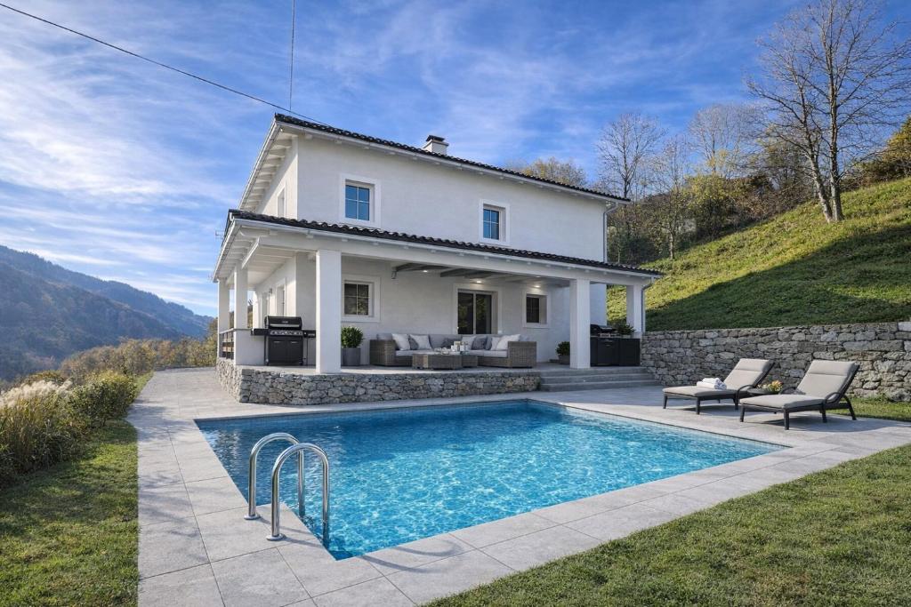 a villa with a swimming pool in front of a house at Ferienhaus Vida in Most na Soči