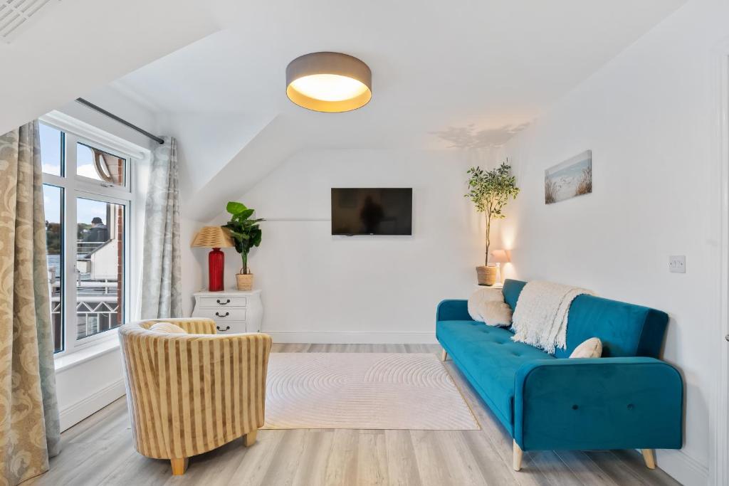 a living room with a blue couch and a window at 5 Rushbrooke Hotel Apartments Cobh County Cork in Cobh
