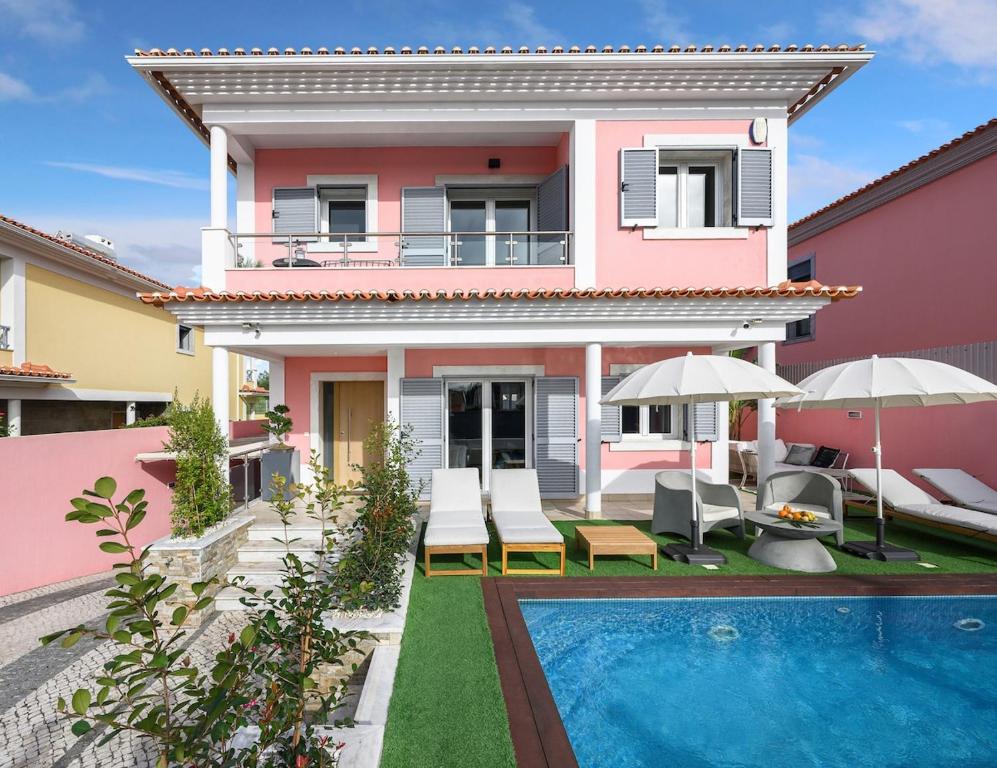 een roze huis met een zwembad ervoor bij Elyra Cascais in Alcabideche