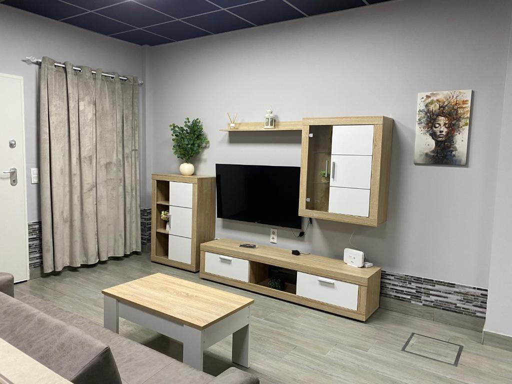 ein Wohnzimmer mit Flachbildfernseher und Tisch in der Unterkunft Miamar in Sevilla