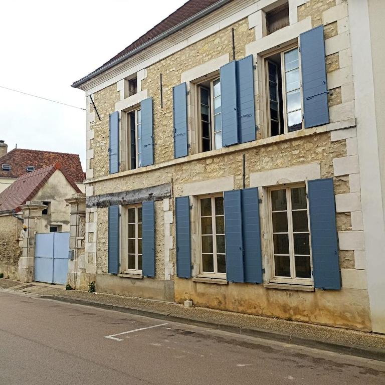 an old building with blue shutters on a street at Mon Jardin Secret in Maligny