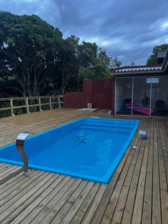 een blauw zwembad op een houten terras bij Gamboa House in Garopaba
