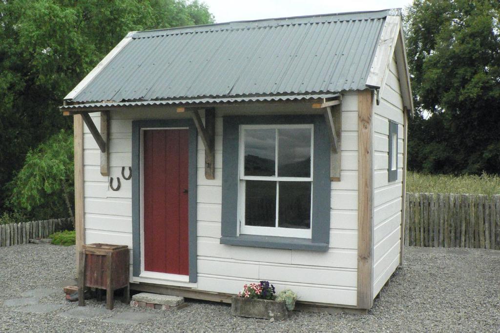 une minuscule maison avec un toit en tôle et une porte rouge dans l'établissement The Old Shepherd, à Masterton