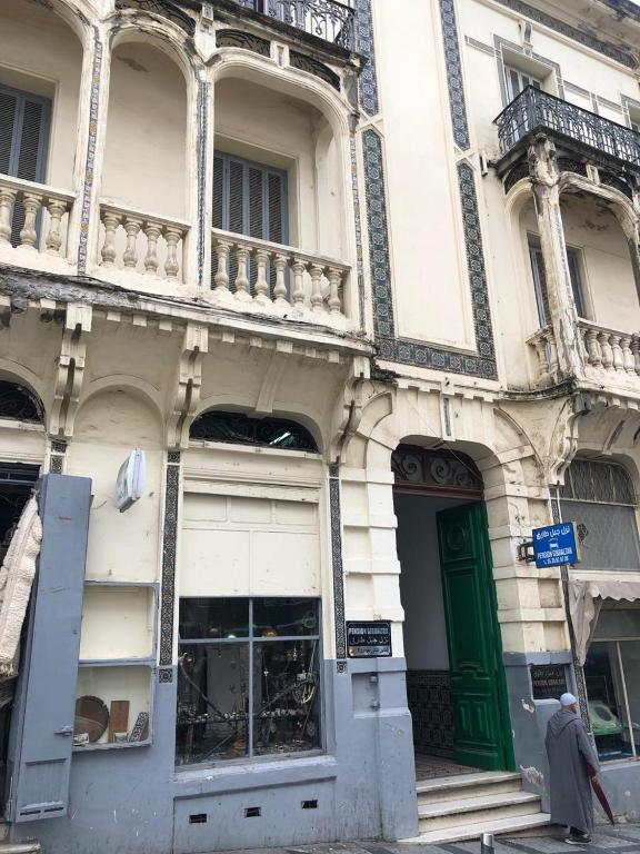 a man walking past a building with a green door at Pension Gibraltar in Tangier