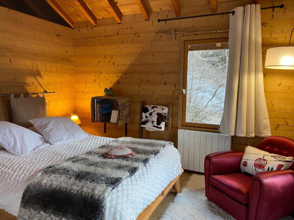 een slaapkamer met een bed, een stoel en een raam bij Chalet la Cabane d'Ernestine, petit-déjeuner inclus in Les Villards-sur-Thônes