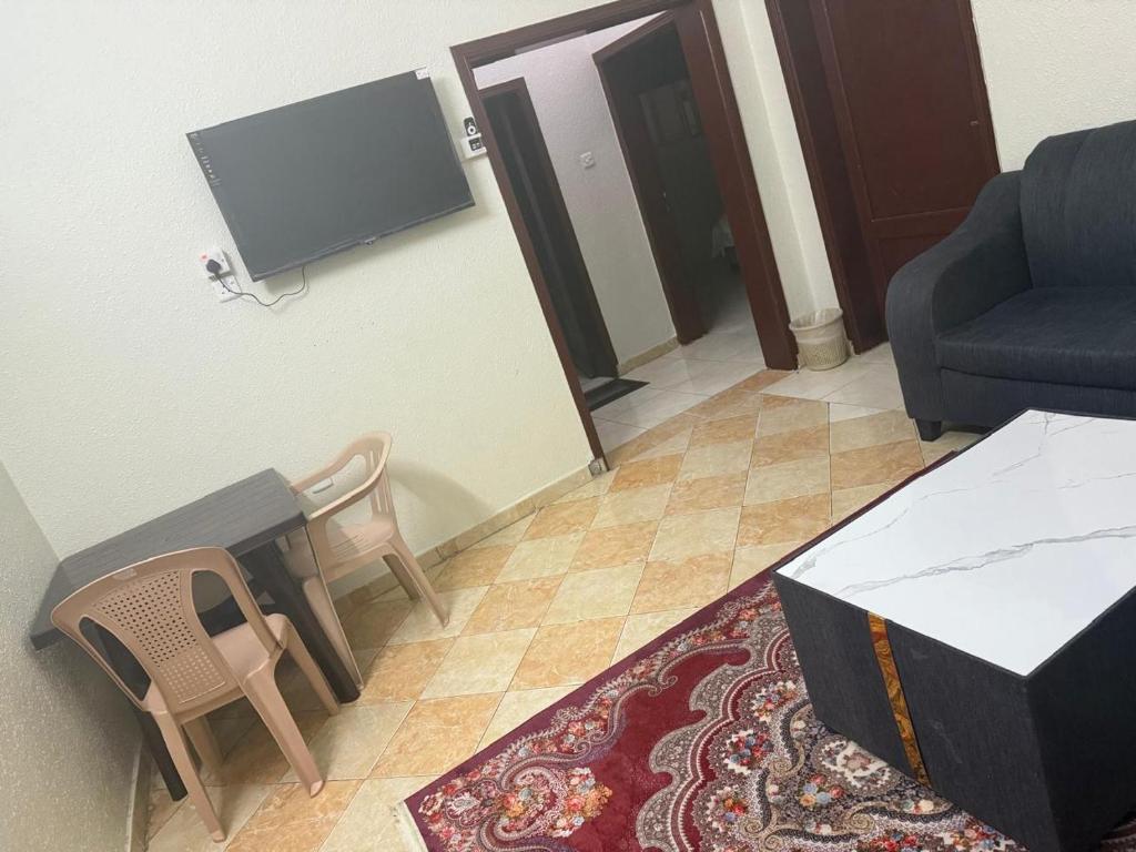 un soggiorno con TV, tavolo e sedie di منار الوجه a Al Wajh
