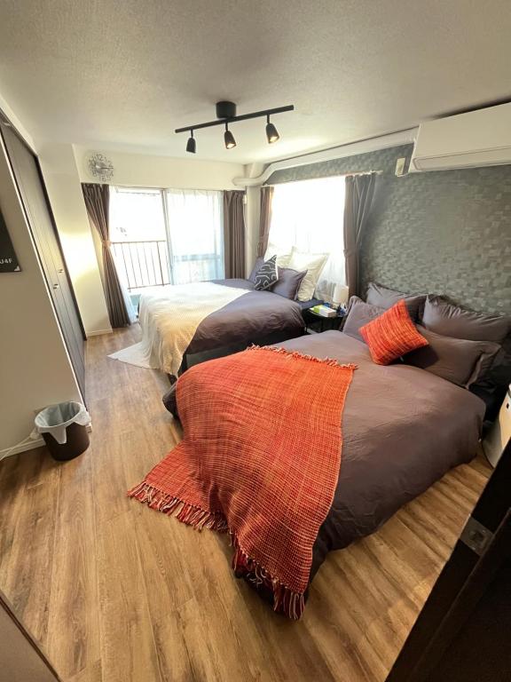 two beds in a bedroom with wood floors at Shimokitazawa Cozy Apartment 401 in Tokyo