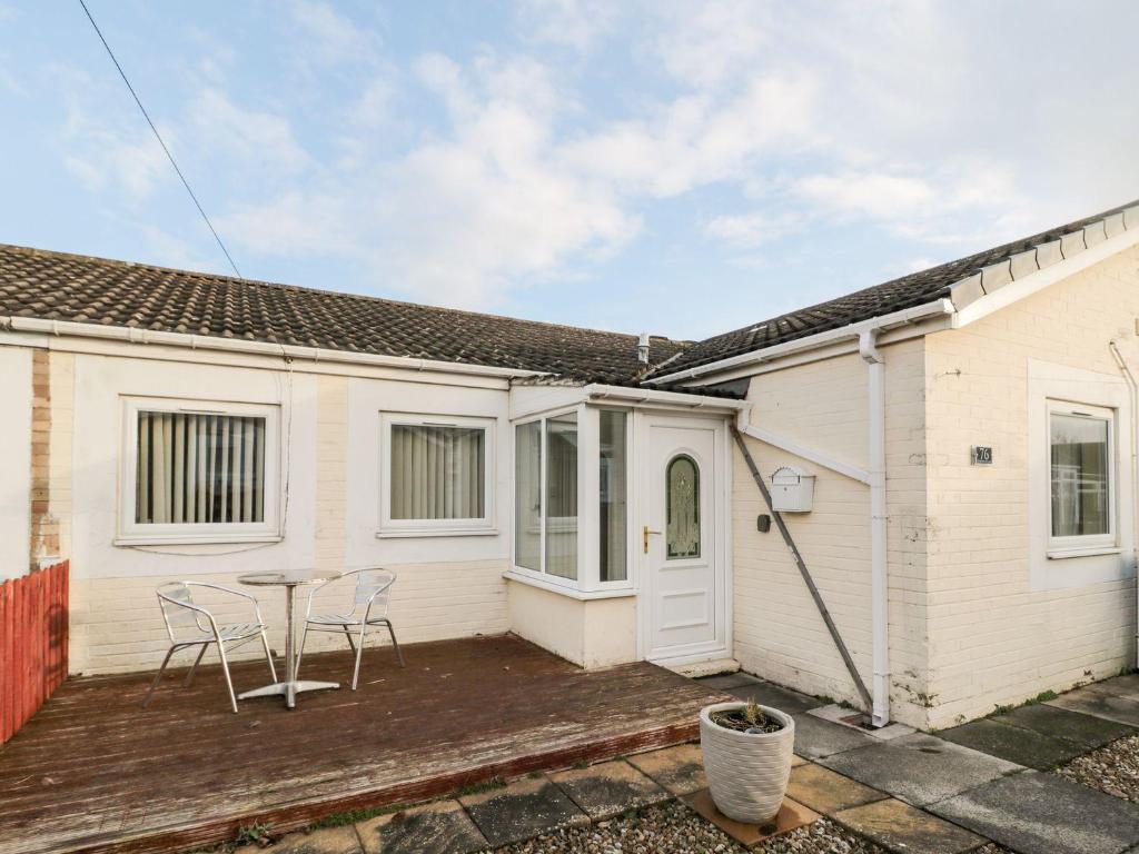 a white house with a patio and a table at Primrose Cottage in Chathill