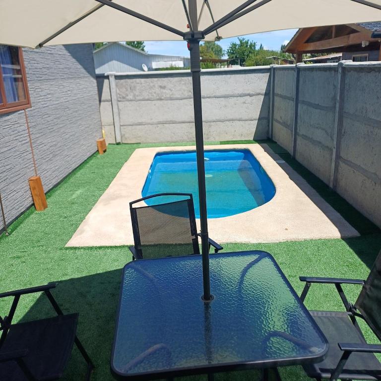 een tafel met een parasol naast een zwembad bij Refugio las Mariposas Chillán in Chillán