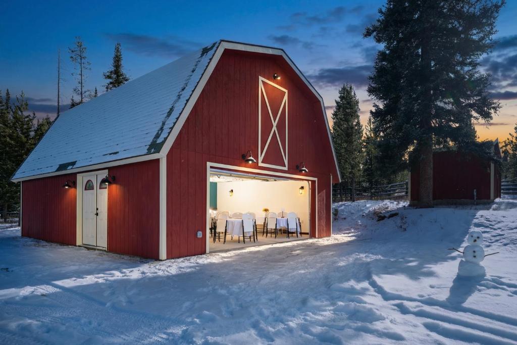 a red barn with white tables and chairs in the snow at Miles Behind Log Cabin in Fraser
