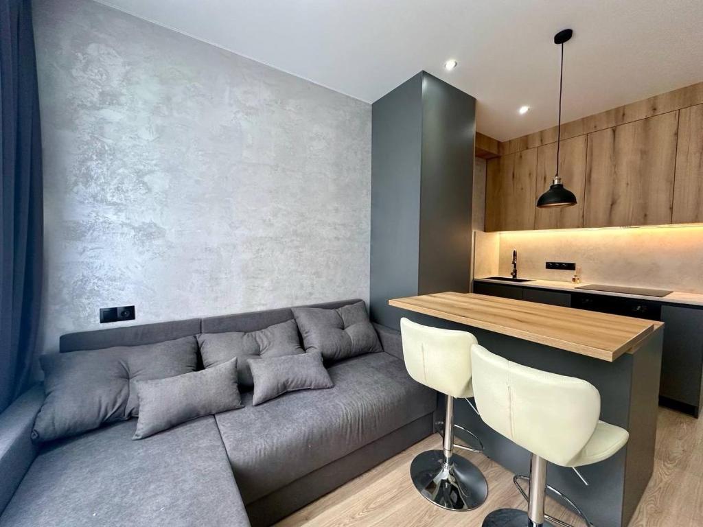 a living room with a gray couch and a kitchen at Central Park Apart Irpin in Irpin