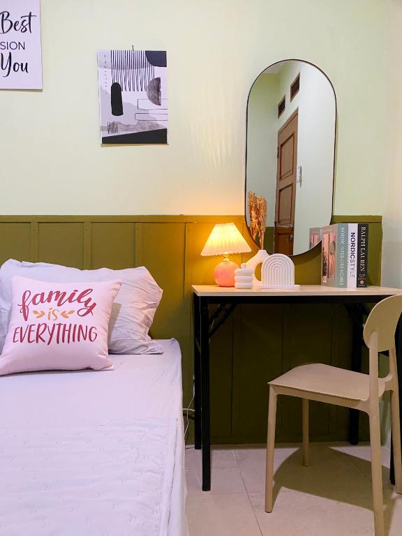 a bedroom with a bed and a desk with a pink pillow at Bandung CoStay in Bandung
