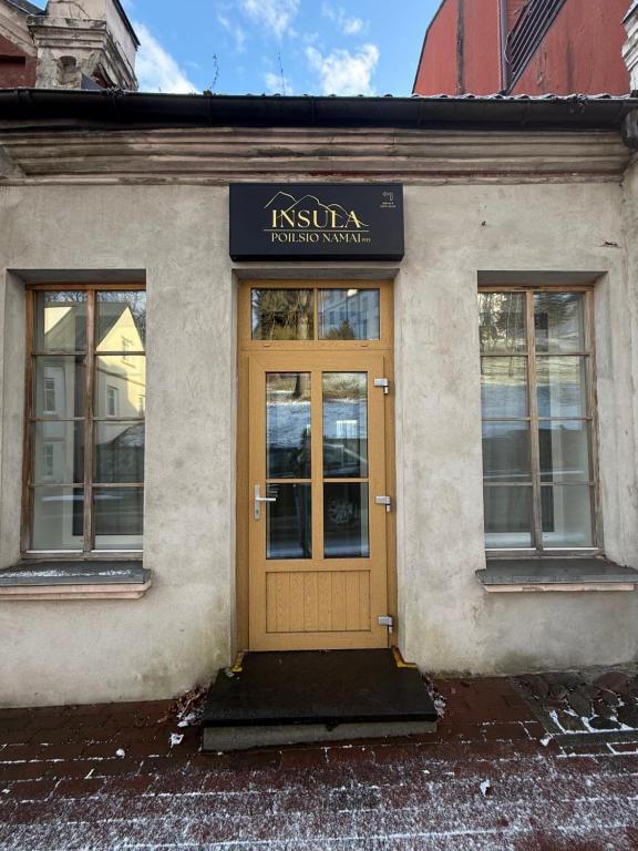a building with a yellow door and windows at Insula Poilsio Namai in Telšiai