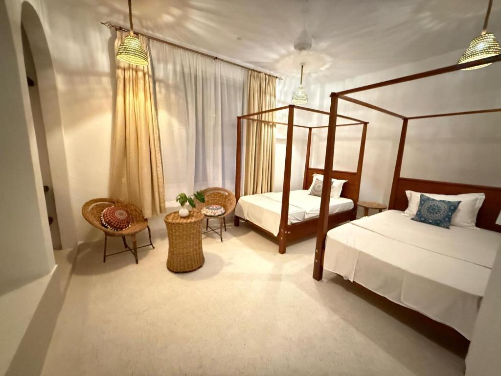 een slaapkamer met 2 bedden en een hemelbed bij Natural living eco resort in Malindi