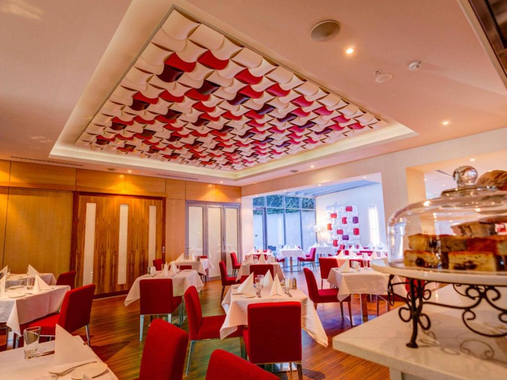 een restaurant met witte tafels en rode stoelen bij Mantra Charles Hotel in Launceston