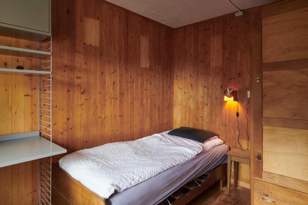 a room with a bed in a wooden wall at Waterfall House - Art and Design, Ski, Hike, Swim in Mesocco