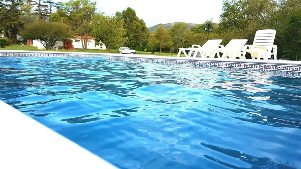 een zwembad met blauw water en witte stoelen bij Casa Punilla in Valle Hermoso