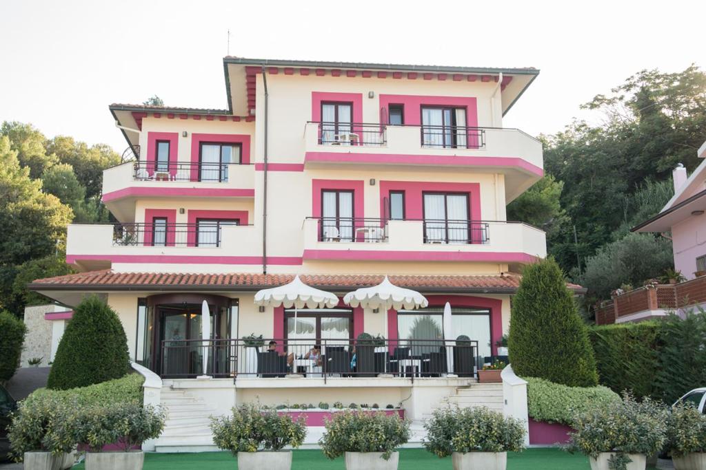 un edificio rosa e bianco con cespugli di fronte di Hotel Levante a Fossacesia