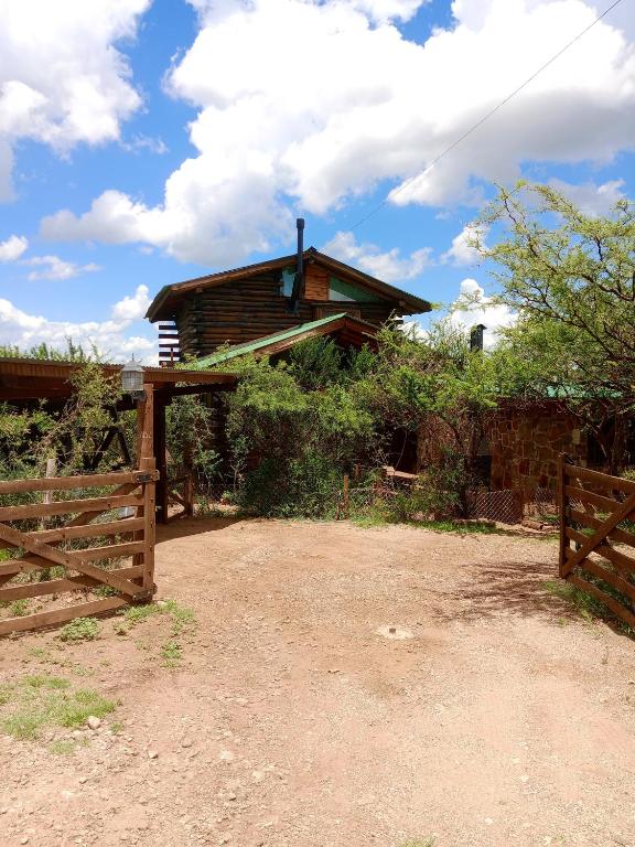 a wooden house with a fence and a gate at Cabaña Alcione in Capilla del Monte
