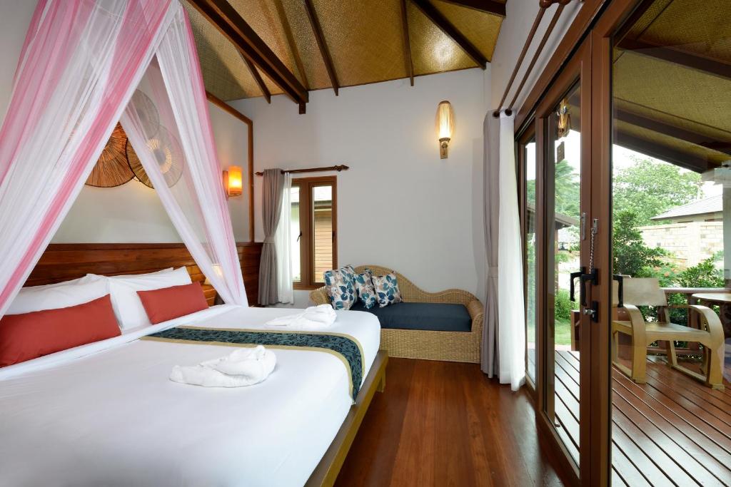 a bedroom with a bed with white sheets and a window at PingChan Koh Phangan Beachfront Resort in Thong Nai Pan Yai