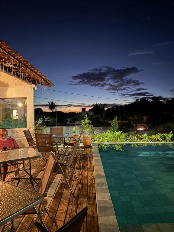 a patio with chairs and a swimming pool at night at Pousada Jeito Bom de Viver in Caraíva