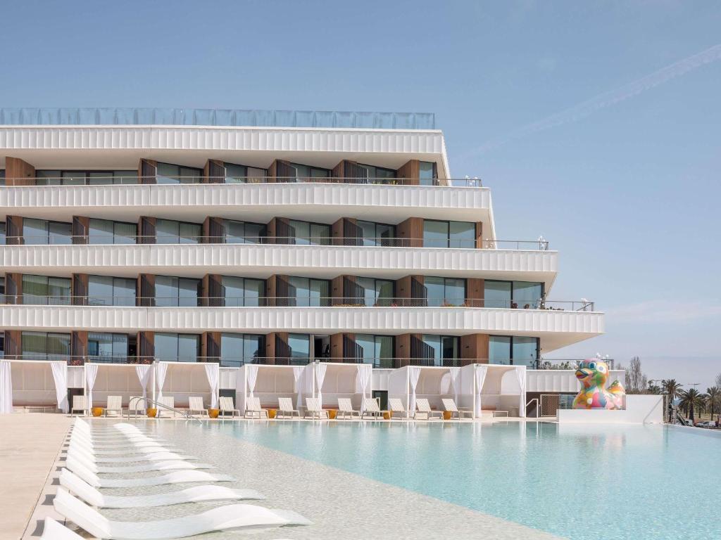a hotel with lounge chairs and a swimming pool at SLS Barcelona in Barcelona