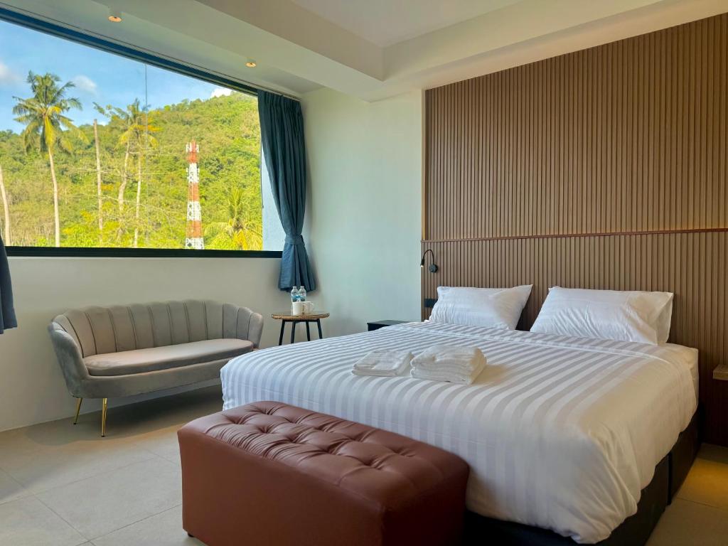 een slaapkamer met een groot bed, een stoel en een raam bij Kefir Phuket in Kamala Beach
