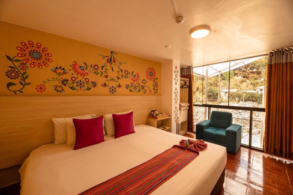 a bedroom with a bed with red pillows and a chair at Mayu Boutique Hotel in Cusco