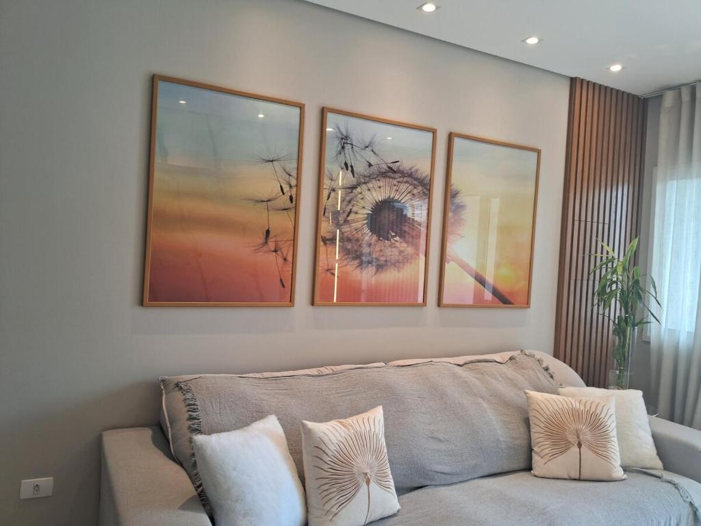 ein Wohnzimmer mit einer Couch und vier Bildern an der Wand in der Unterkunft Calmaria in Matinhos